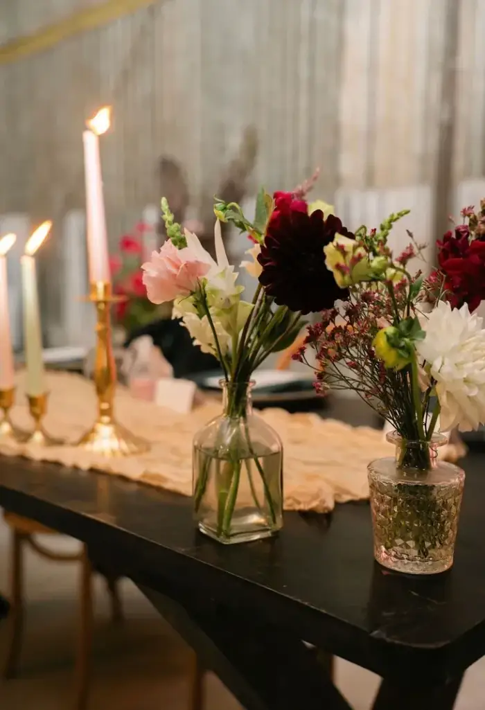 Candlelit reception table styled with bud vases and burgundy flowers