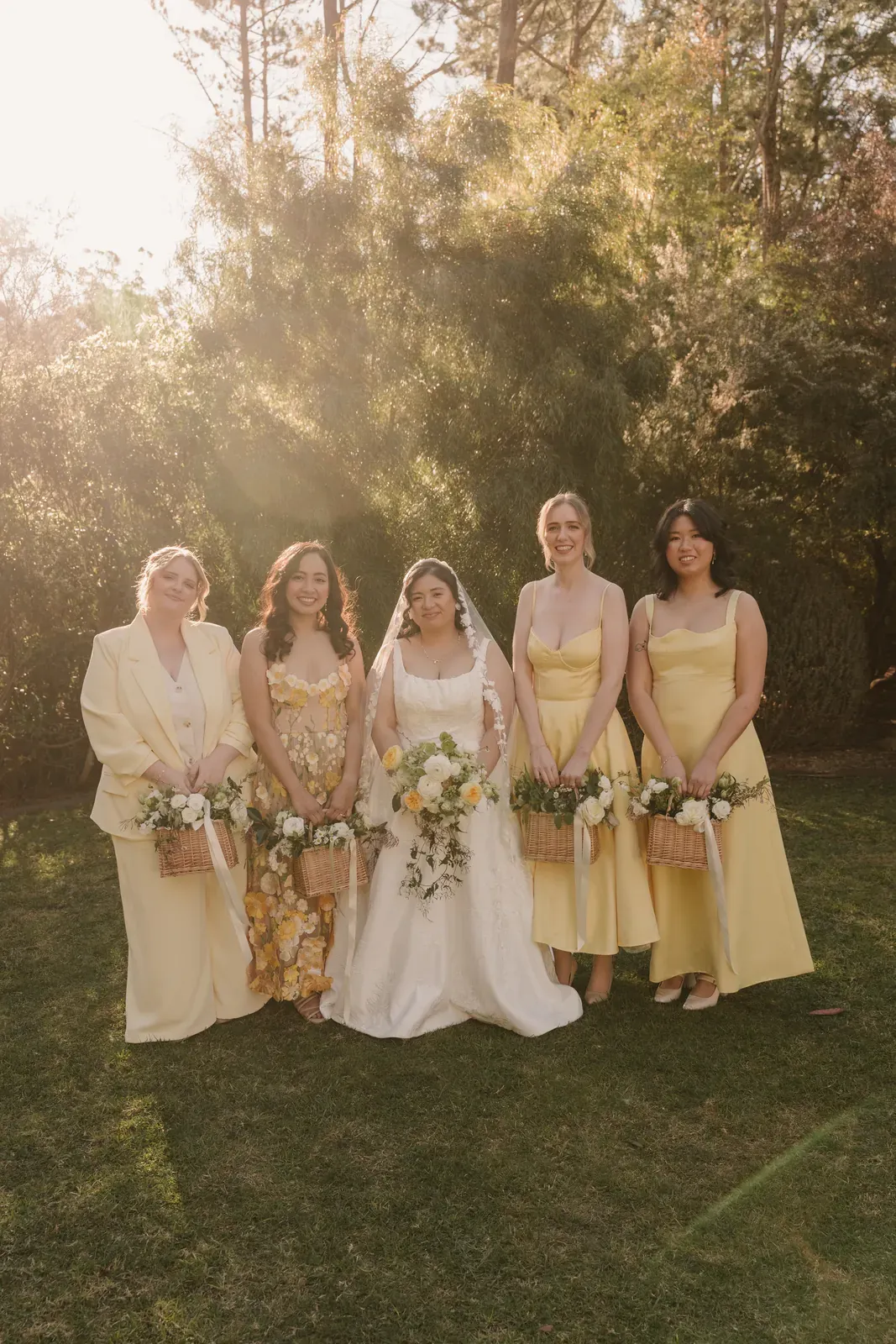 Bride with four bridesmaids in yellow, each holding a white and yellow bouquet