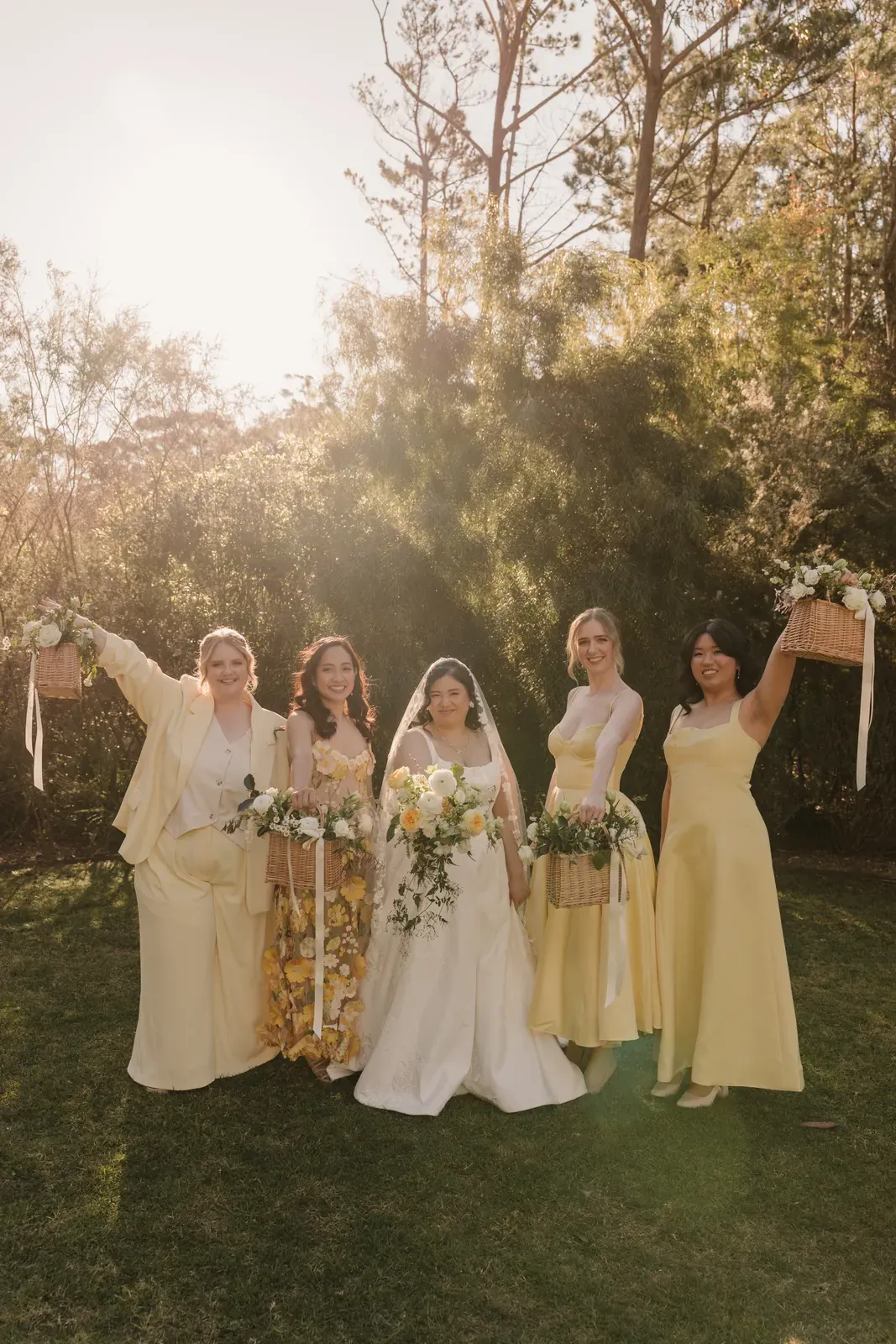 Bridal party cheering with arms raised, bouquets in hand