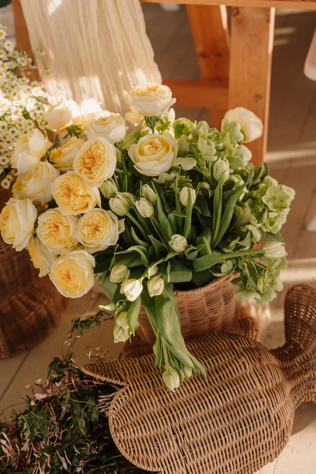 Close-up of yellow roses and white tulips arranged in a wicker basket