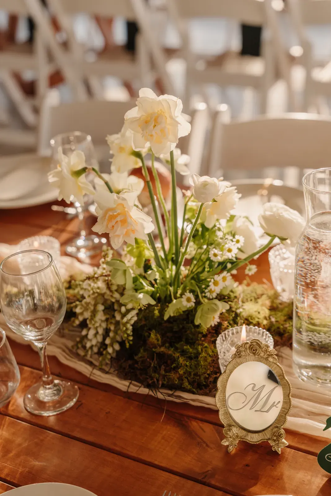 Timber reception table centrepiece of white flowers and moss