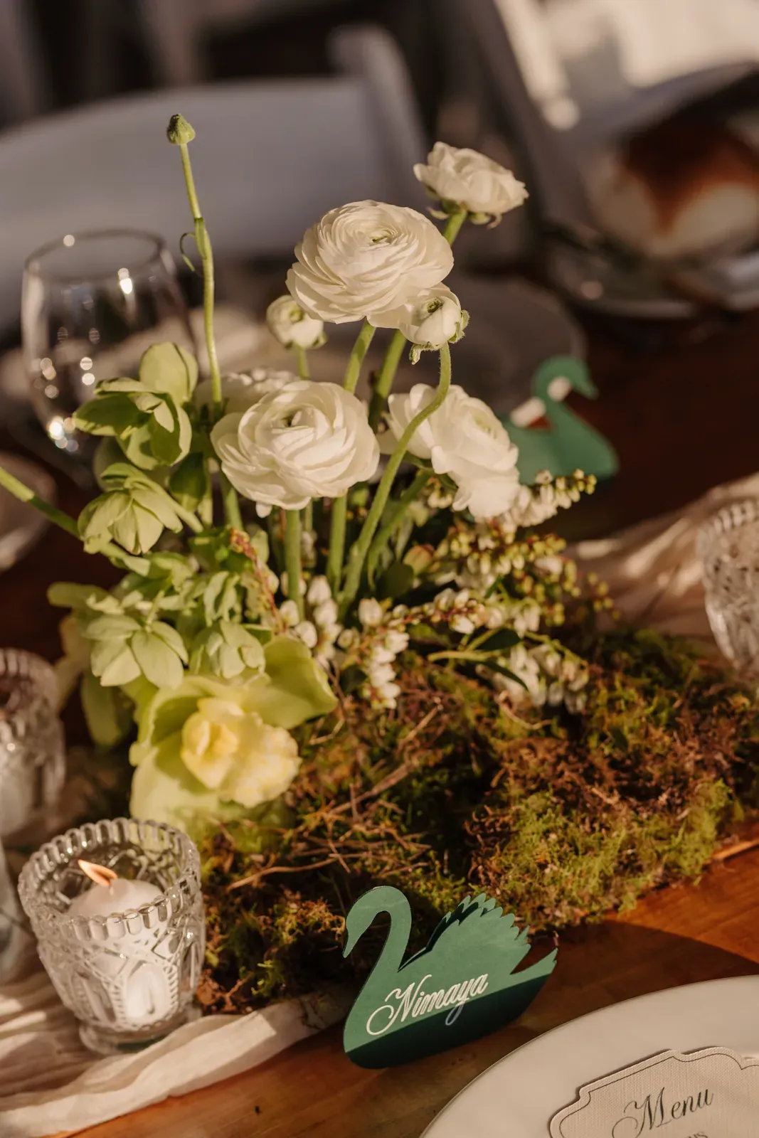 Close-up of white ranunculus and moss running along a reception table