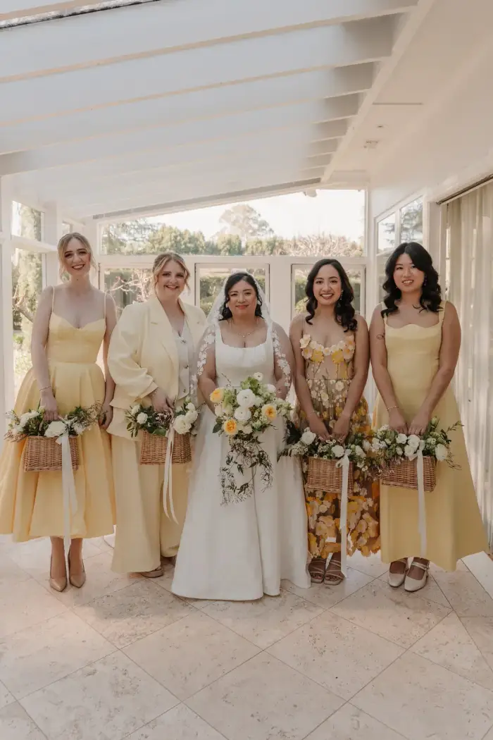 Bride and bridesmaids in yellow with their bouquets in a garden room