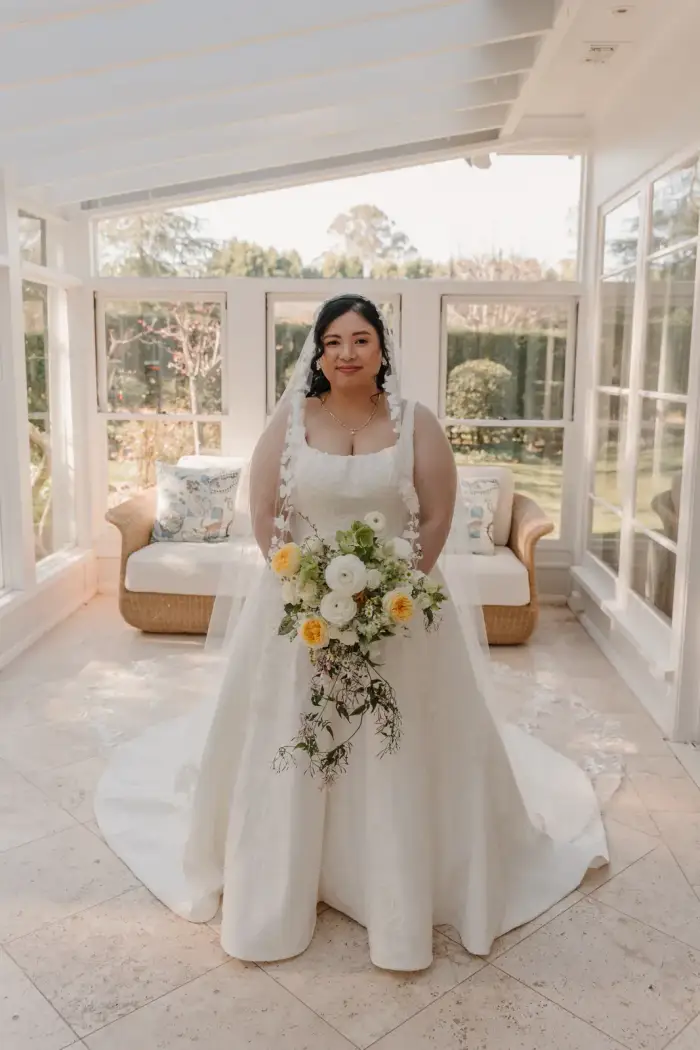 Bride indoors holding a cascading yellow and white bouquet