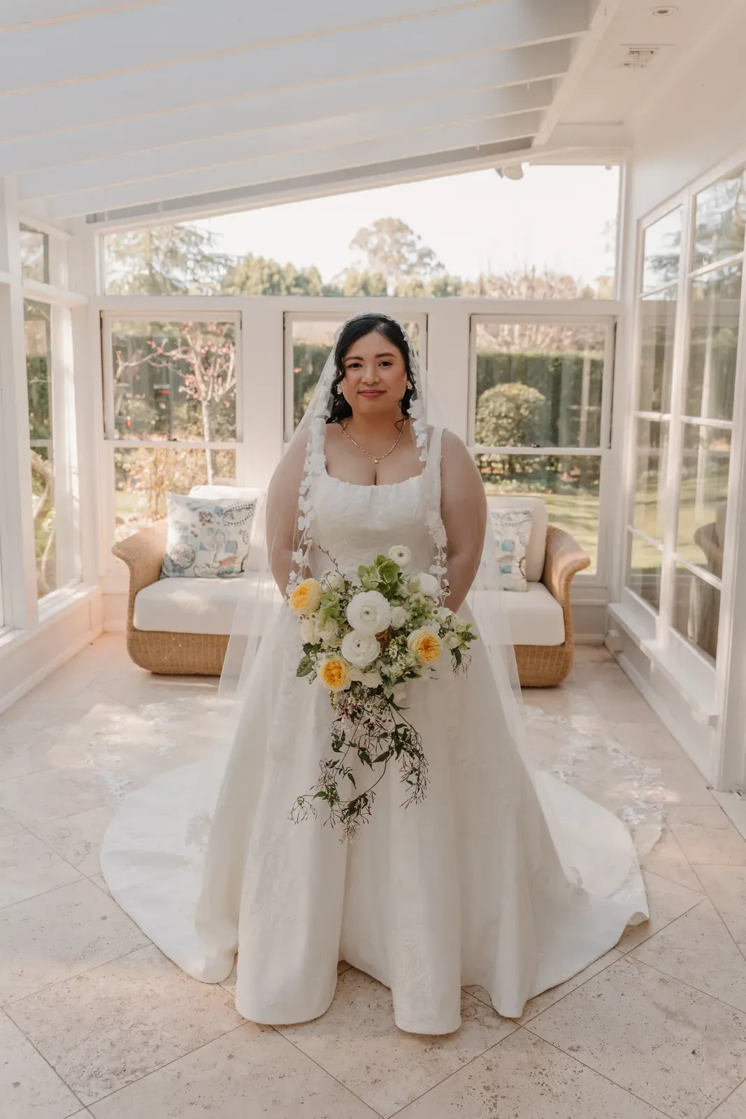Bride indoors holding a cascading yellow and white bouquet