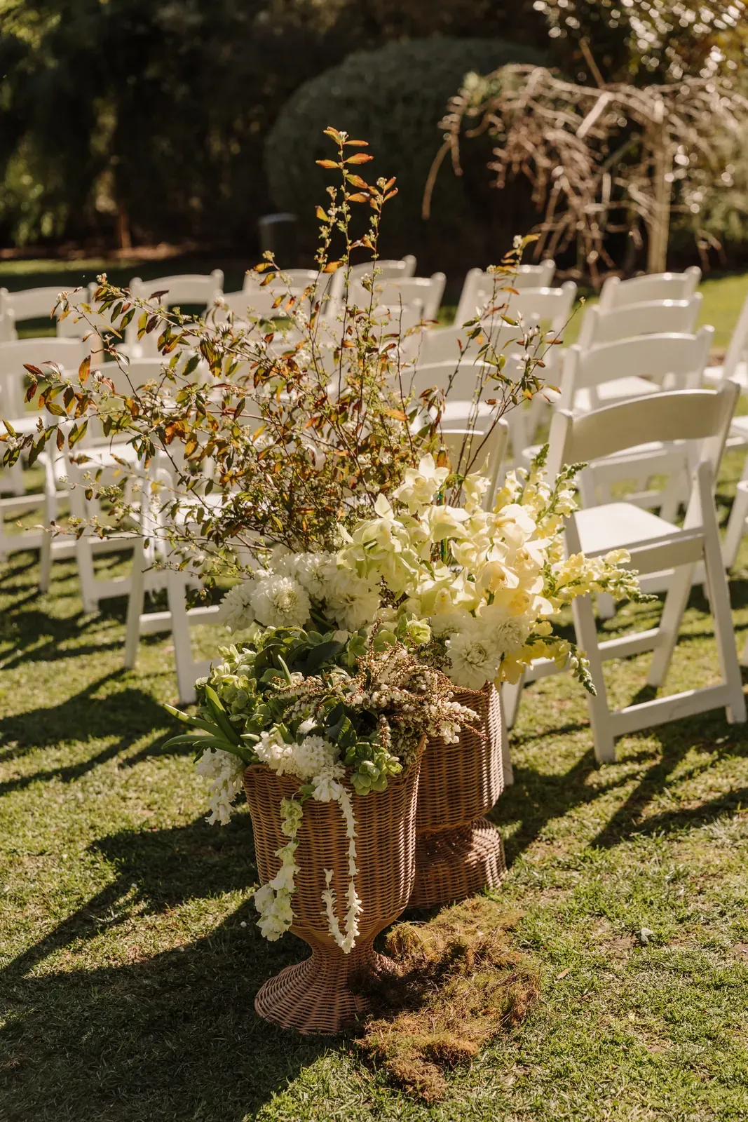 Aisle arrangement of white and yellow flowers in a woven basket