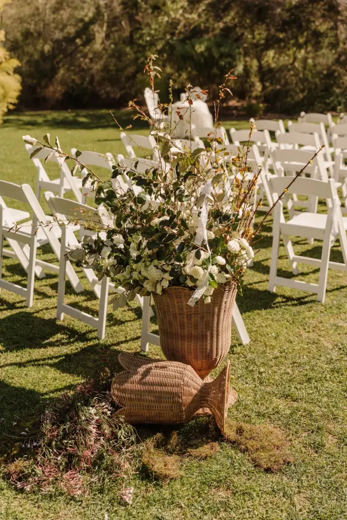 Basket aisle arrangement with blossom branches beside the ceremony seating