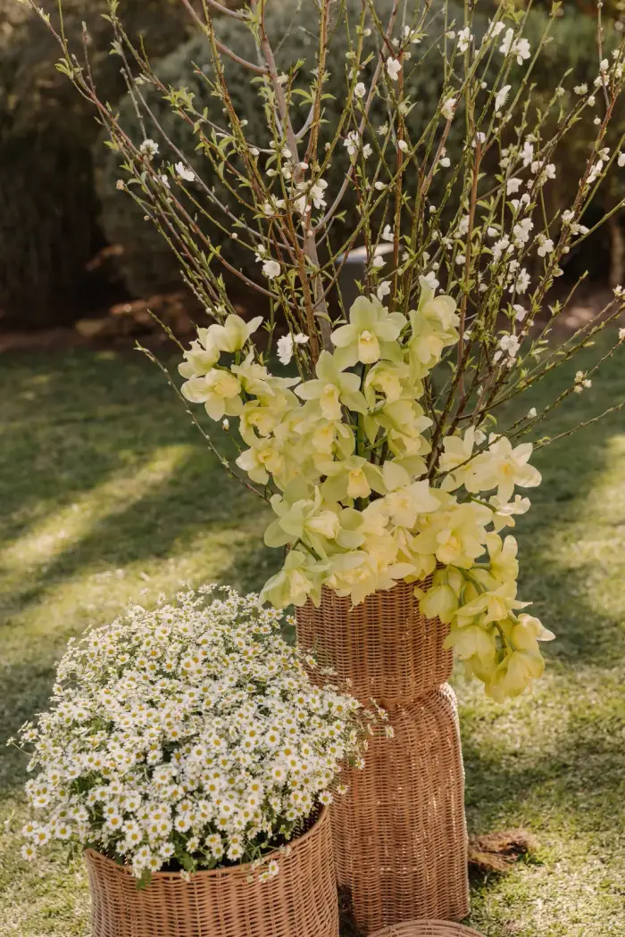 Tall blossom branch arrangement with white flowers in woven baskets