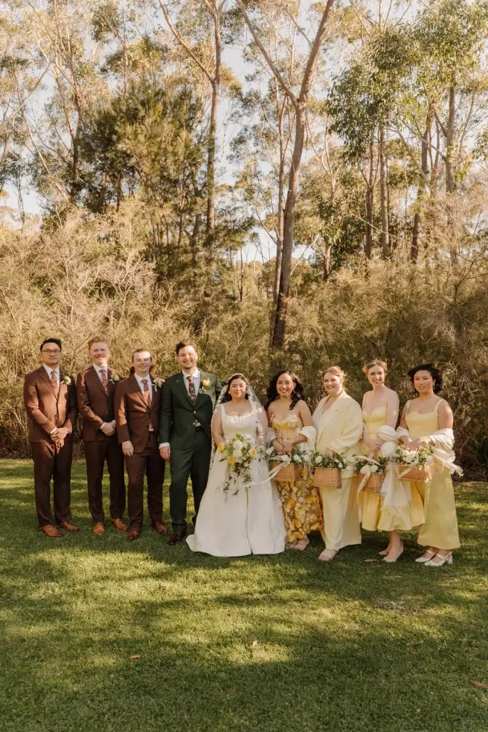 The full bridal party in yellow and burgundy on the ceremony lawn