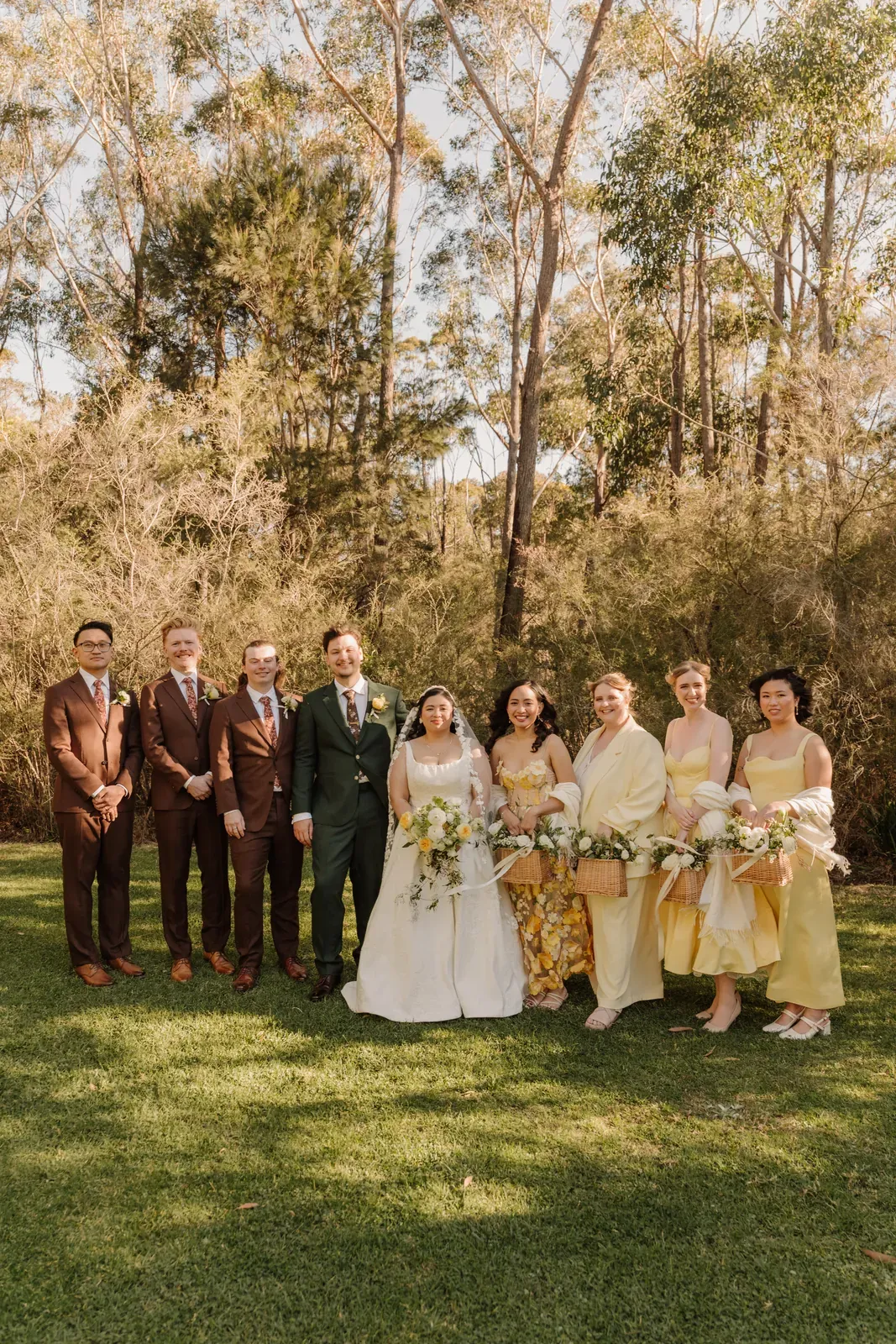 The full bridal party in yellow and burgundy on the ceremony lawn