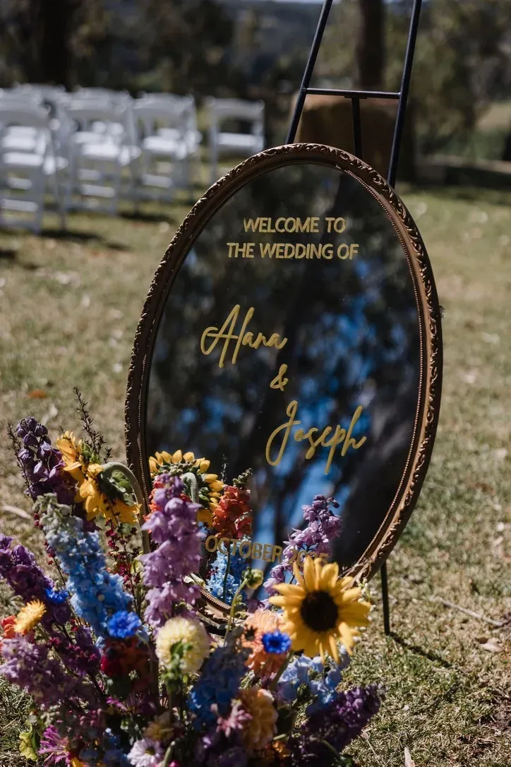 Welcome sign for Alana & Joseph's wedding, framed with a wildflower arrangement