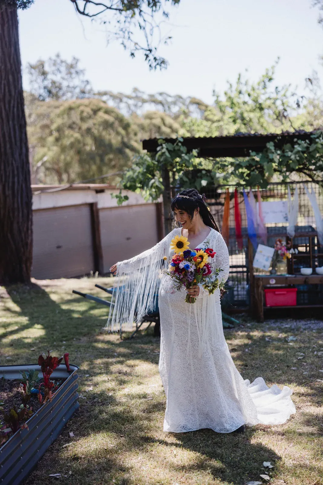 Bride in a boho lace dress holding a sunflower and wildflower bouquet
