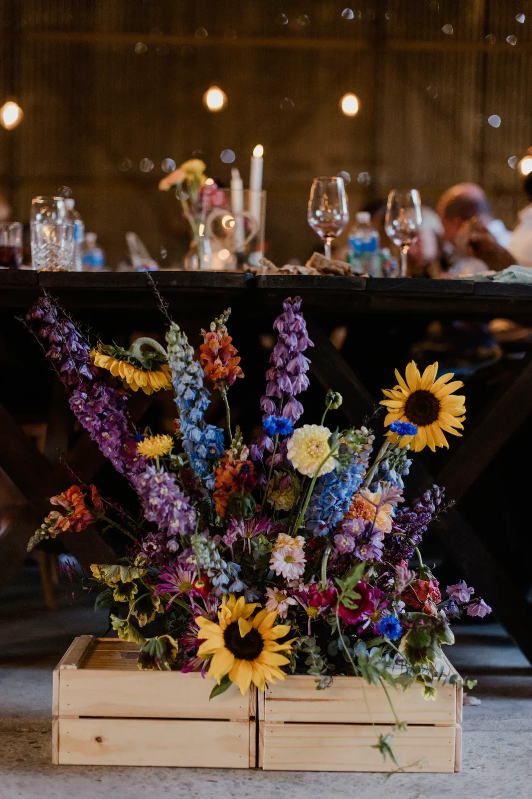 Wildflower centrepiece with sunflowers and delphinium in a wooden crate on the reception table