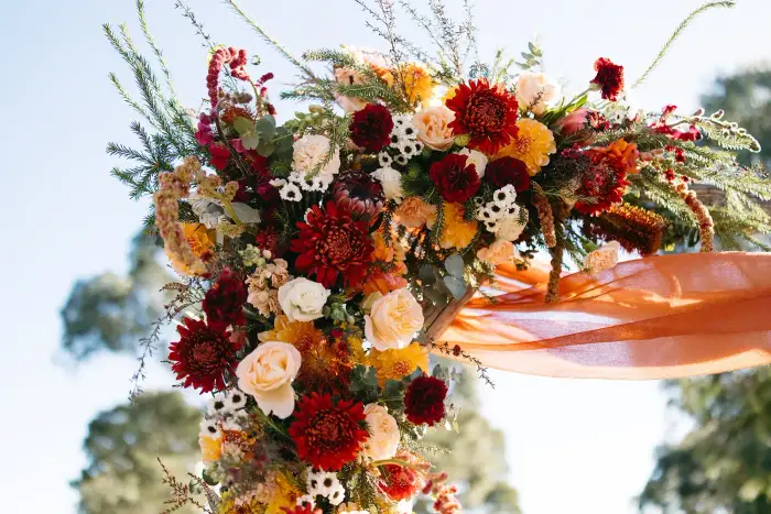 Close-up of a burgundy, rust and cream floral ceremony arrangement