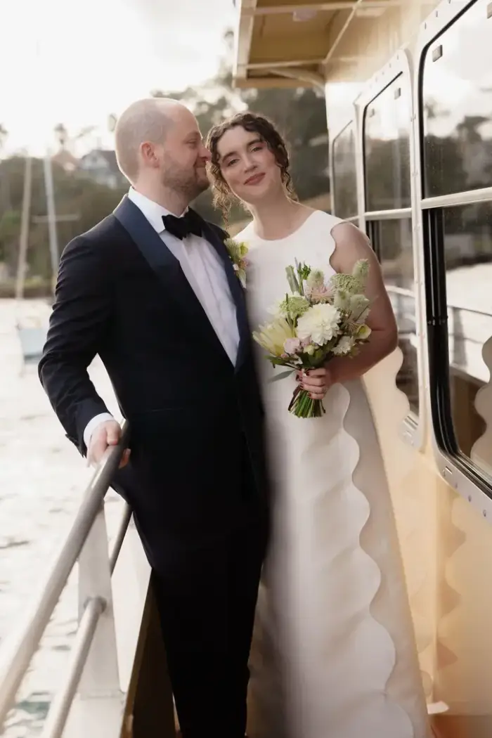 Bride and groom on a ferry at dusk, the bride holding a white bouquet