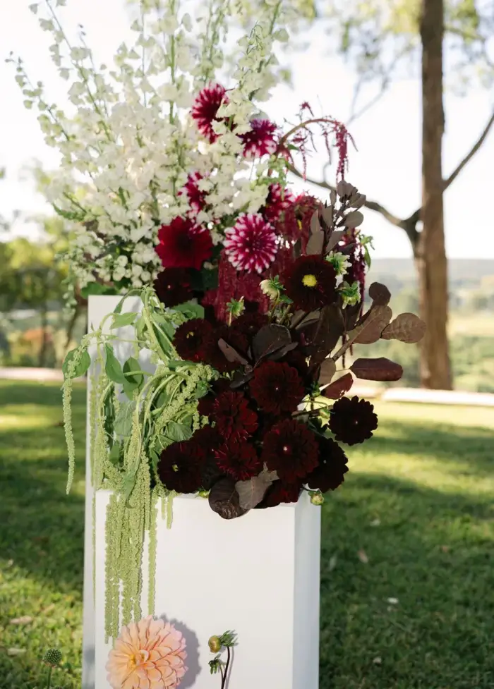 Burgundy and white ceremony flowers arranged on modern plinths