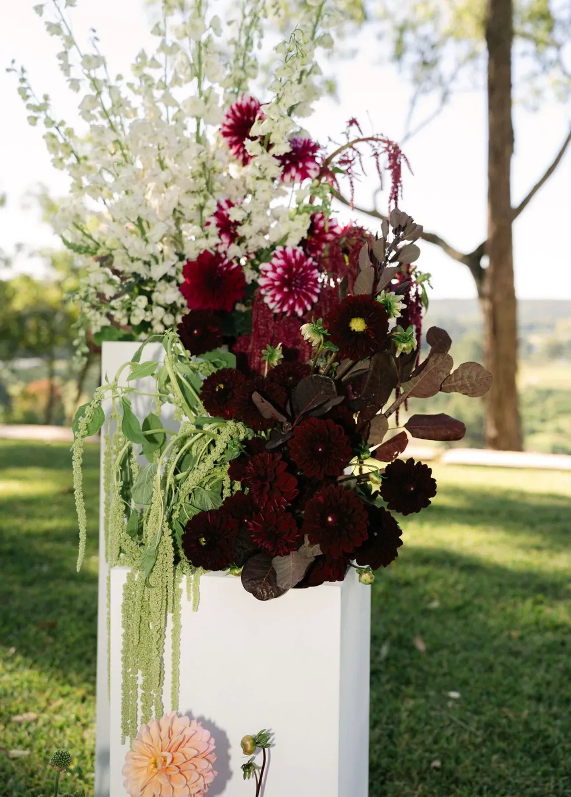 Burgundy and white ceremony flowers arranged on modern plinths